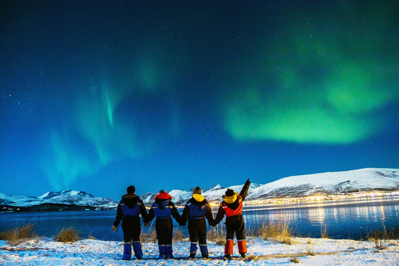 tourists watching the aurora borealis by the water