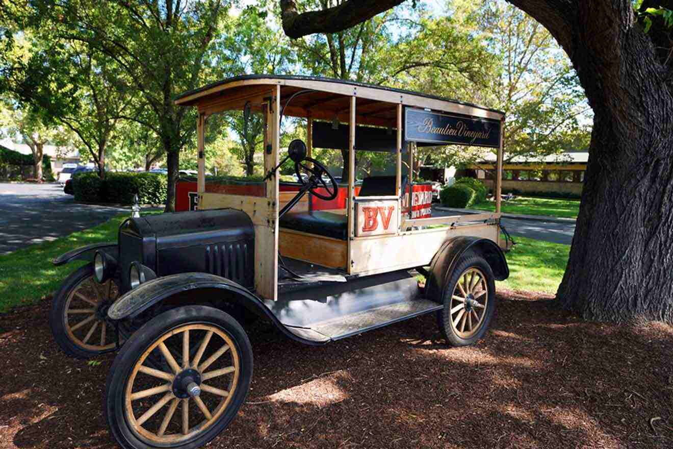 an old fashioned car is parked under a tree