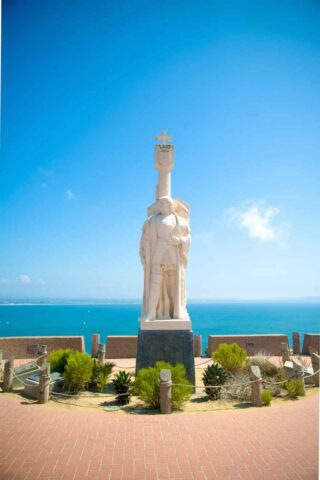 statue of a man with the ocean in the background