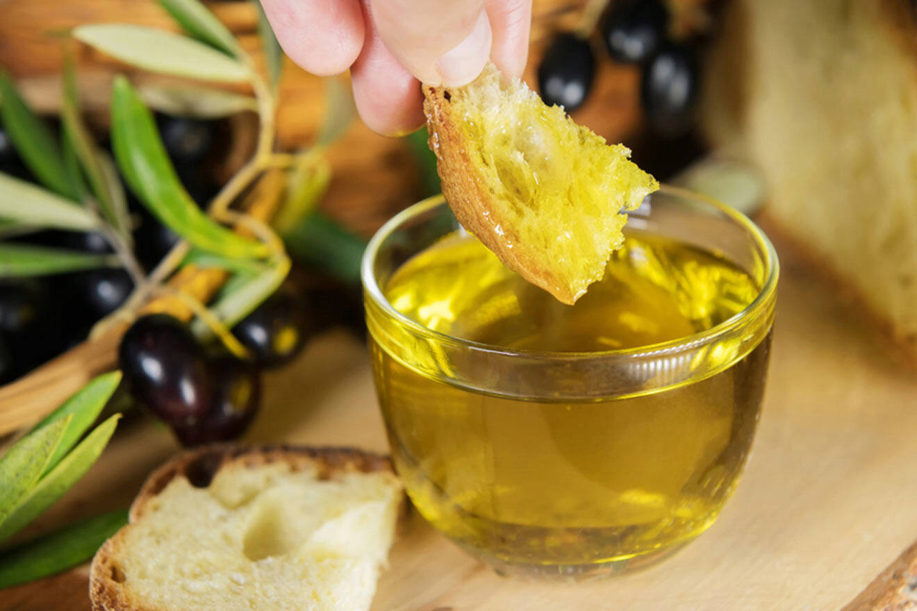 a person dipping olives into a glass of olive oil