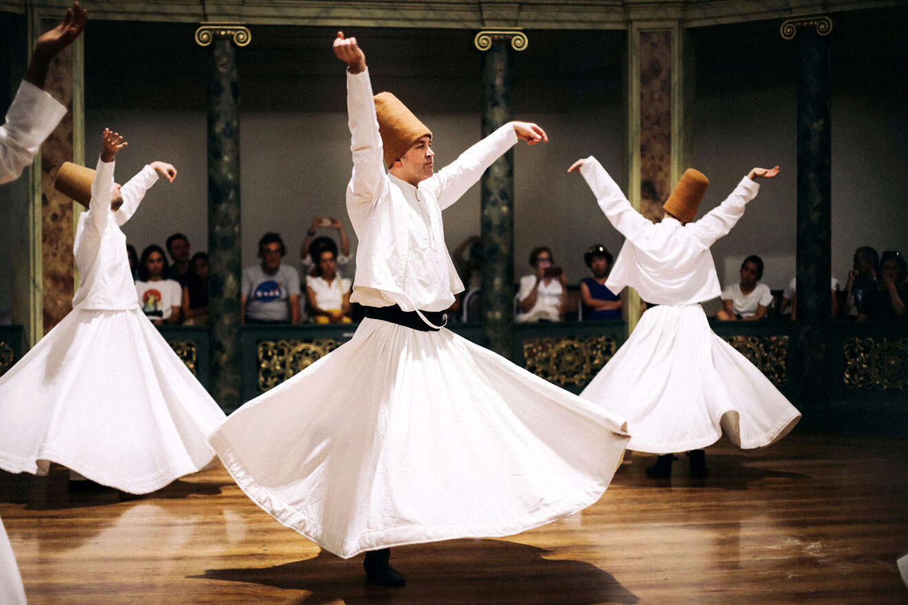 a group of people dancing the Whirling Dervish dance on a wooden floor