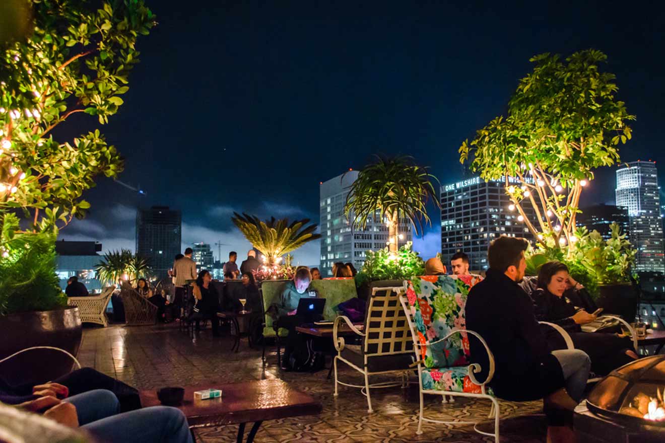 people sit at tables in a rooftop restaurant at night
