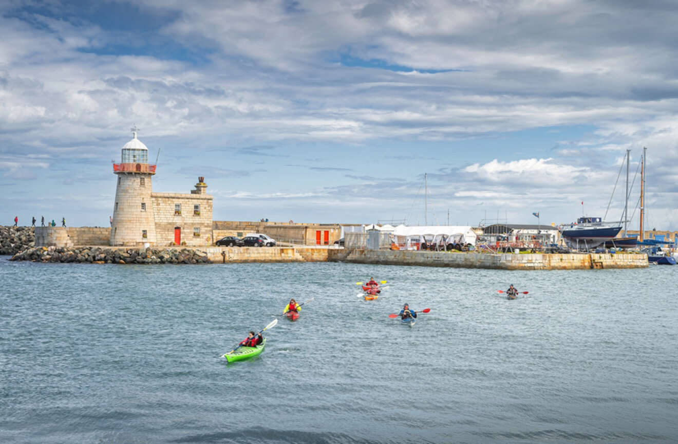 a group of people in kayaks in front of a lighthouse