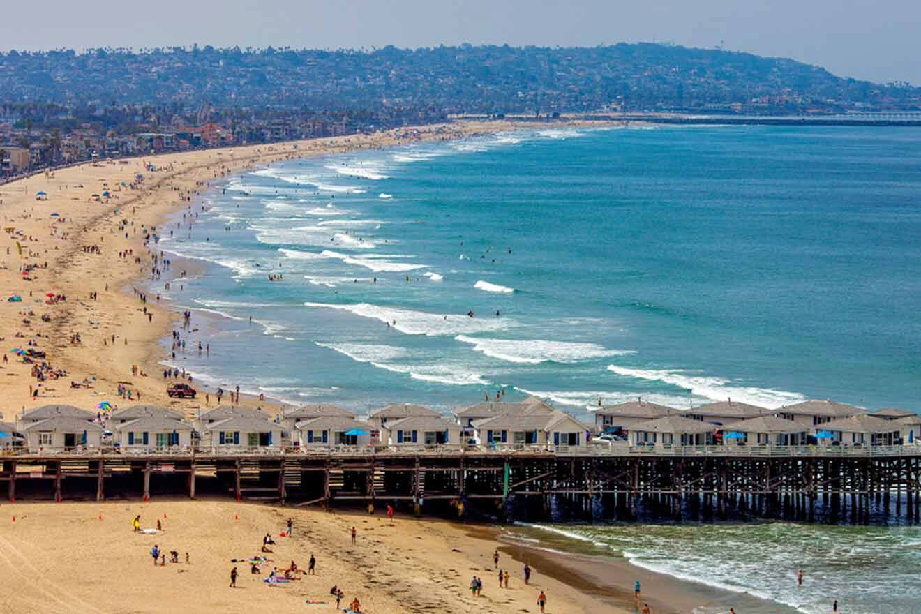 aerial view over a beach with lots of tourists and the pier