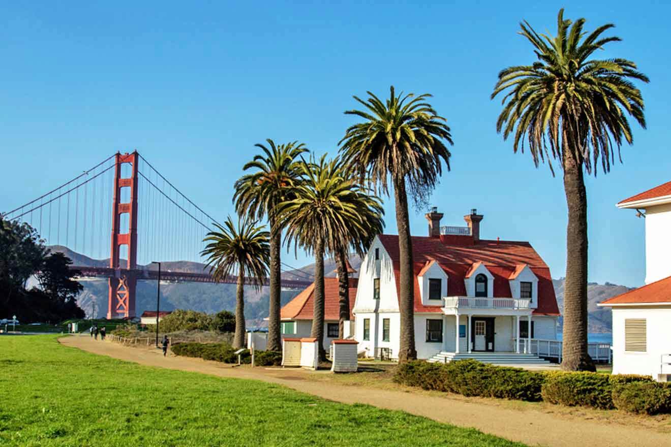 a white house with palm trees and a bridge in the background