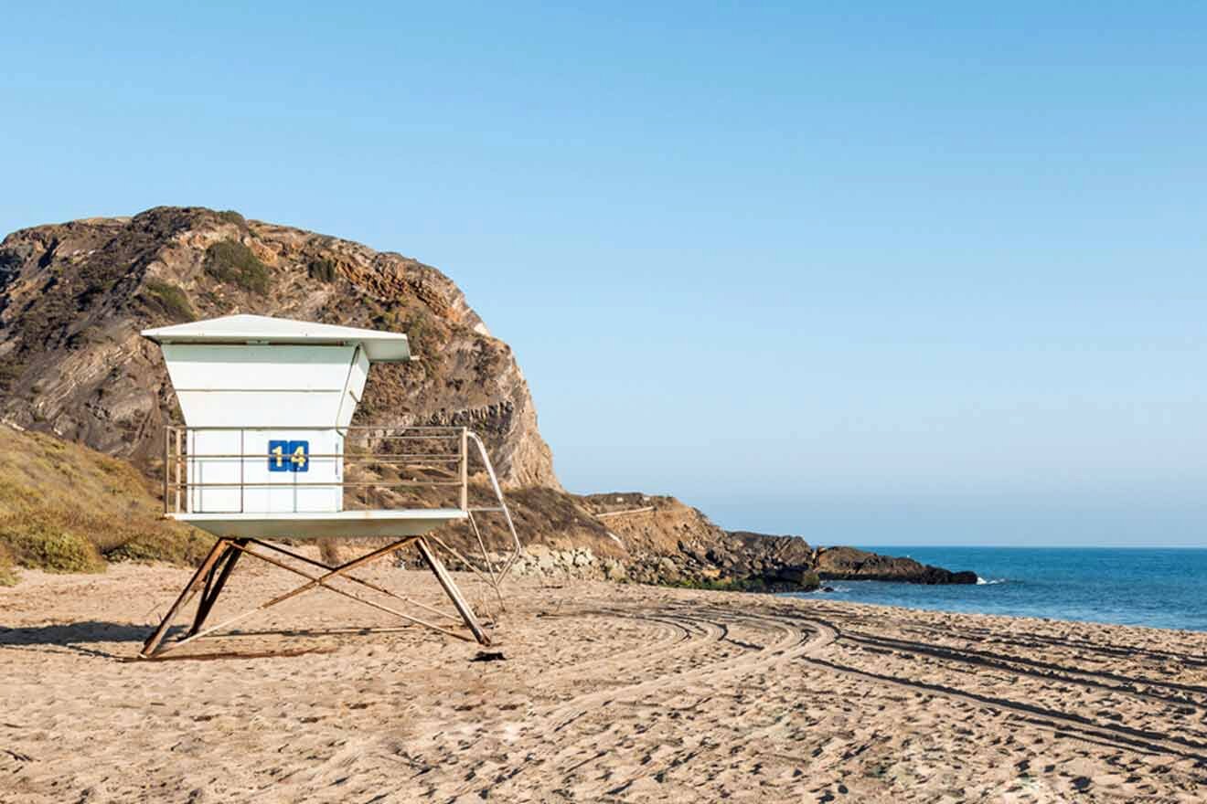 lifeguard tower on a white, sandy beach with a cliff in the background