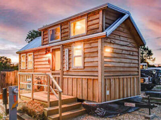 a wooden cabin next to parked cars