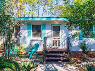 a bungalow with wooden chairs next to it