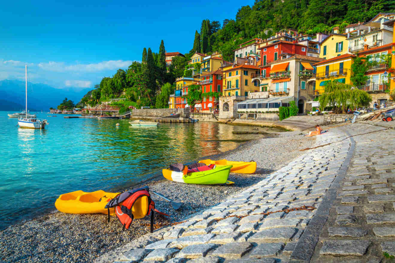 a group of kayaks sitting on top of a beach and colored houses on background