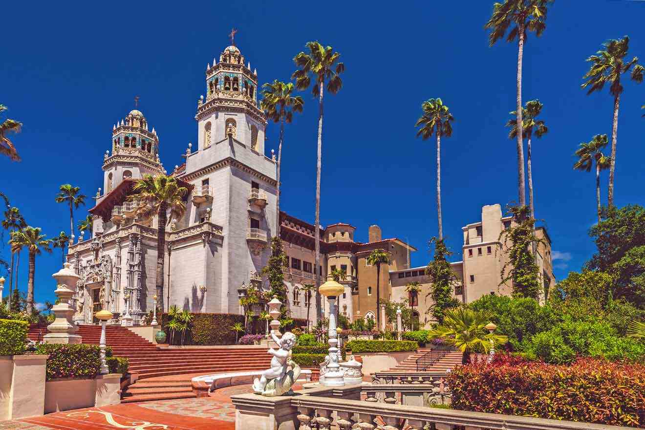 a large white castle with stairs, statues and palm trees