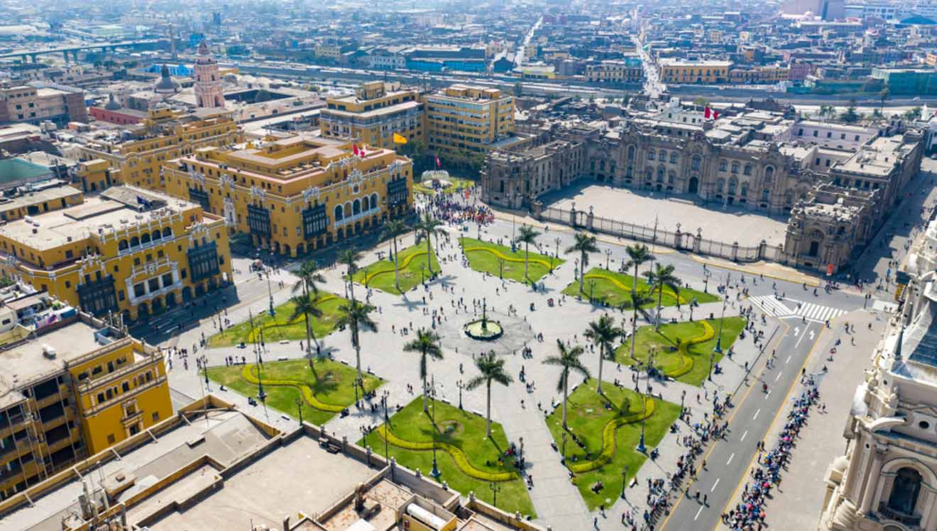 aerial view of the historical center in Lima featuring the main square with grass and palm trees surrounded by city buildings