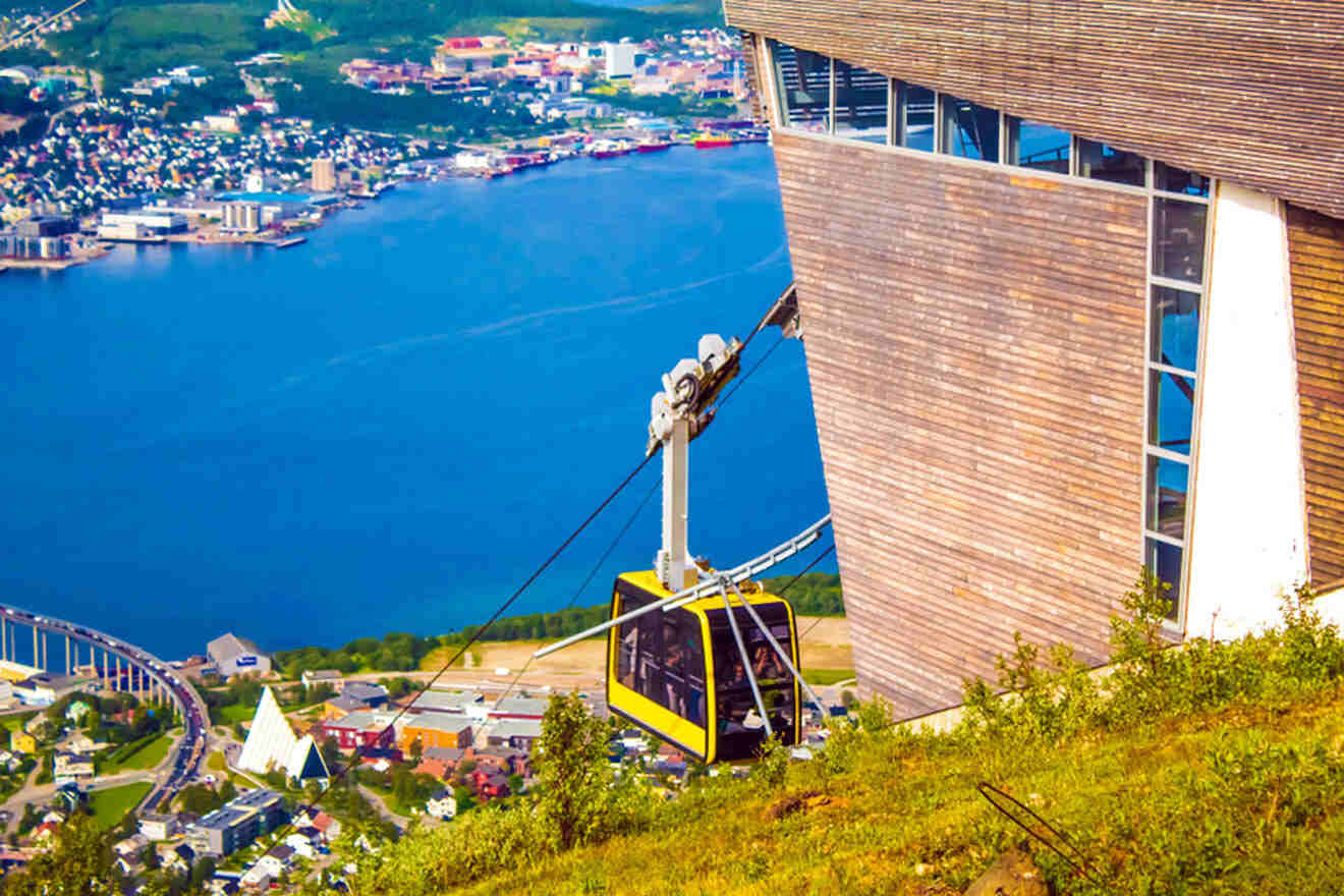 a cable car going up the side of a mountain and a city and water in the background