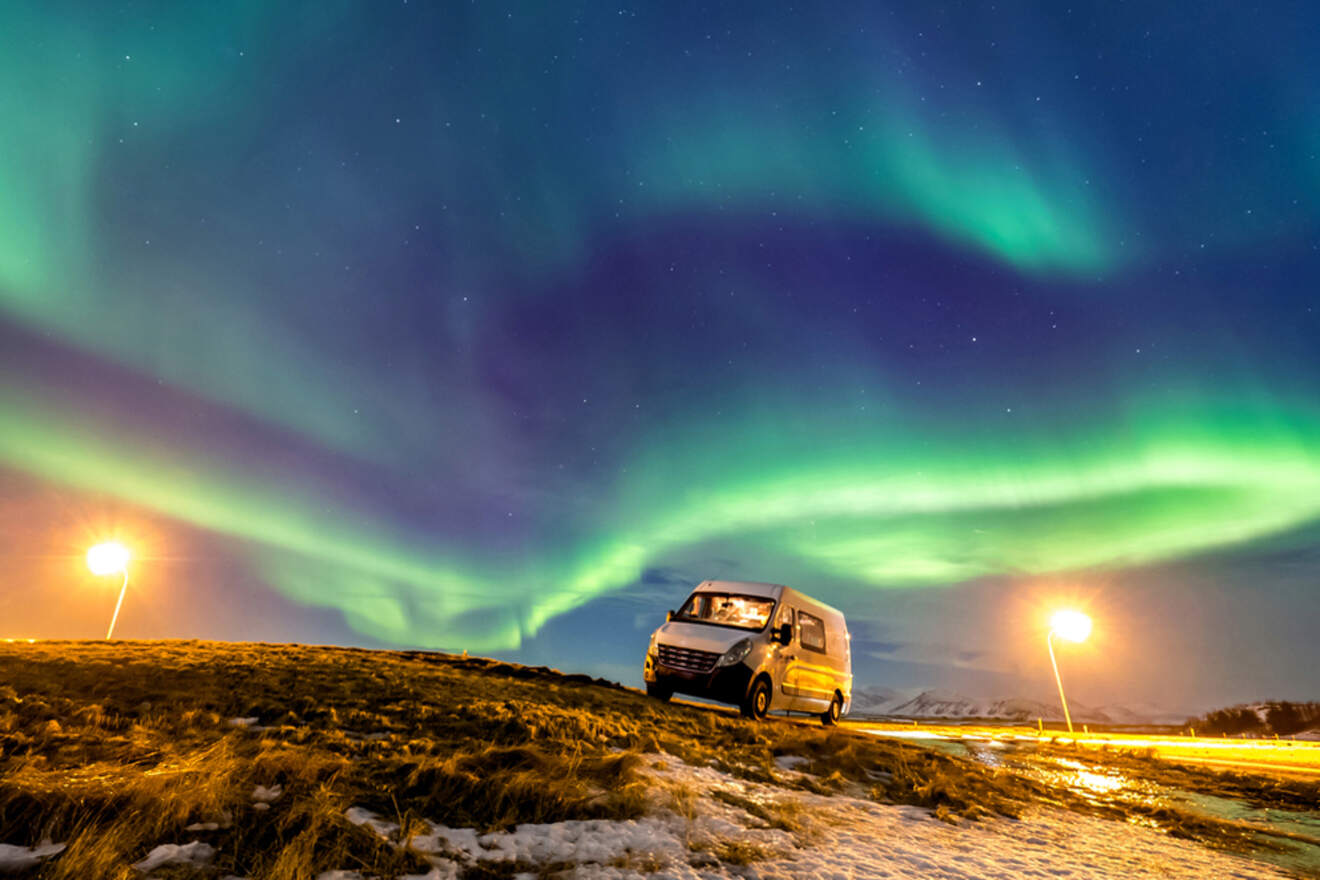 minibus on a field with the northern lights on the sky