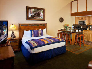 hotel's bedroom with bed,tv stand next to a kitchenette