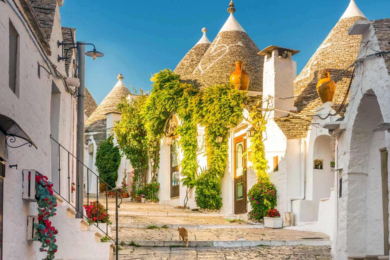 a cobblestone street lined with white trulli houses