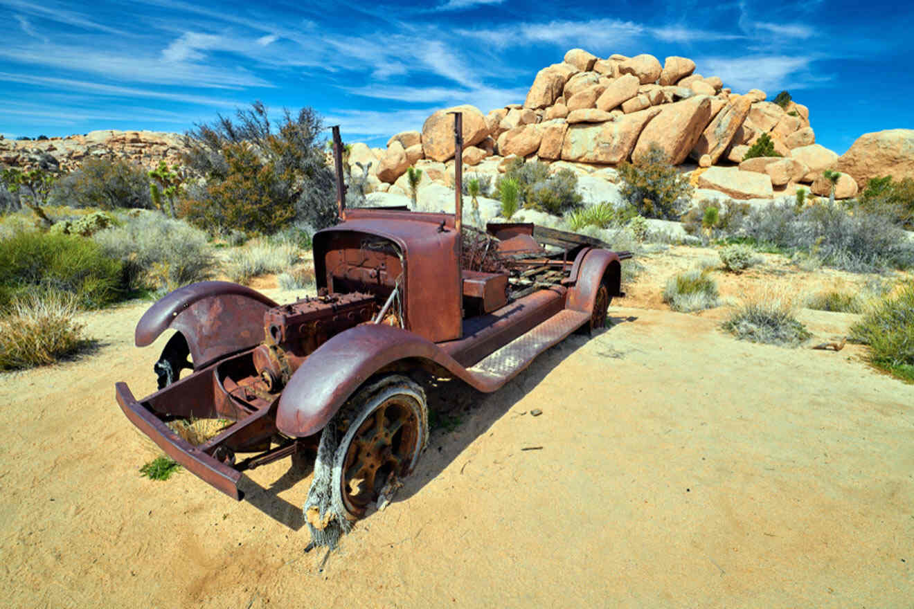 an old rusted out truck sitting in the desert