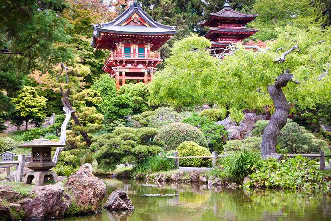 a small pond surrounded by trees and rocks and Japanese buildings