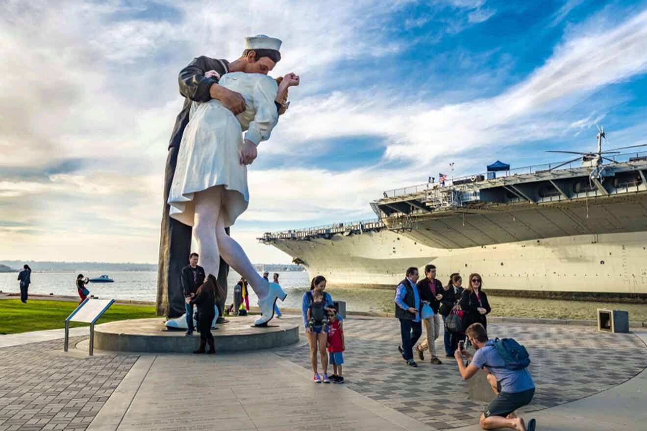 large statue of a man and woman next to a large ship in the uss midway museum