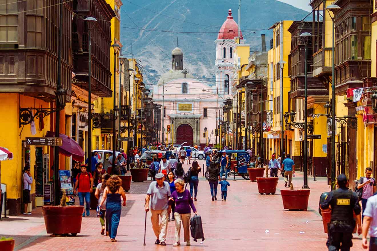 people walking along a crowded street in  with a church at the end of it in Pueblo Libre in Lima
