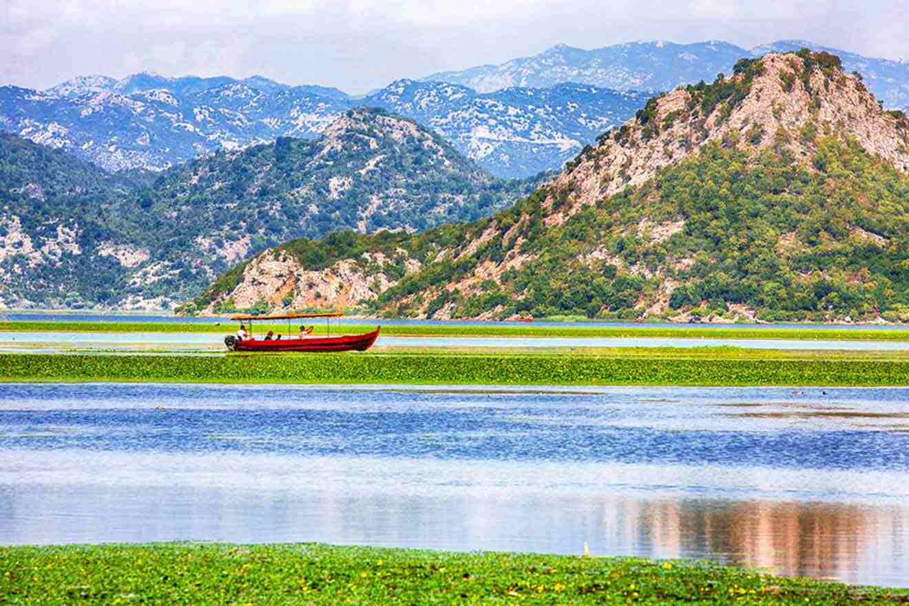 a red boat floating on top of a lake surrounded by mountains