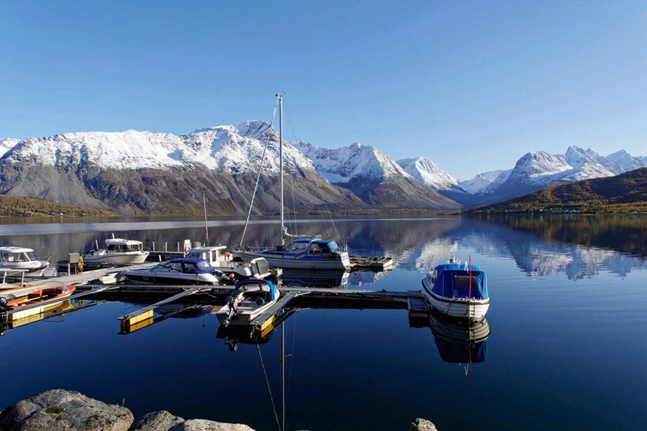 a group of boats that are sitting in the water and snowy mountains in the background