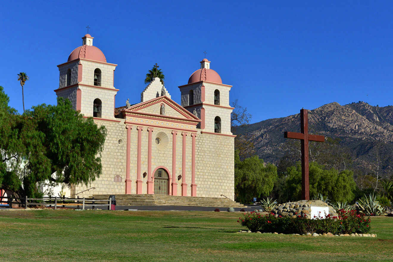 a building with 2 towers and with a cross in front of it