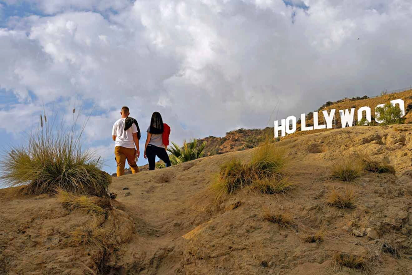 a couple of people that are standing on a hiking trail near the Hollywood sign