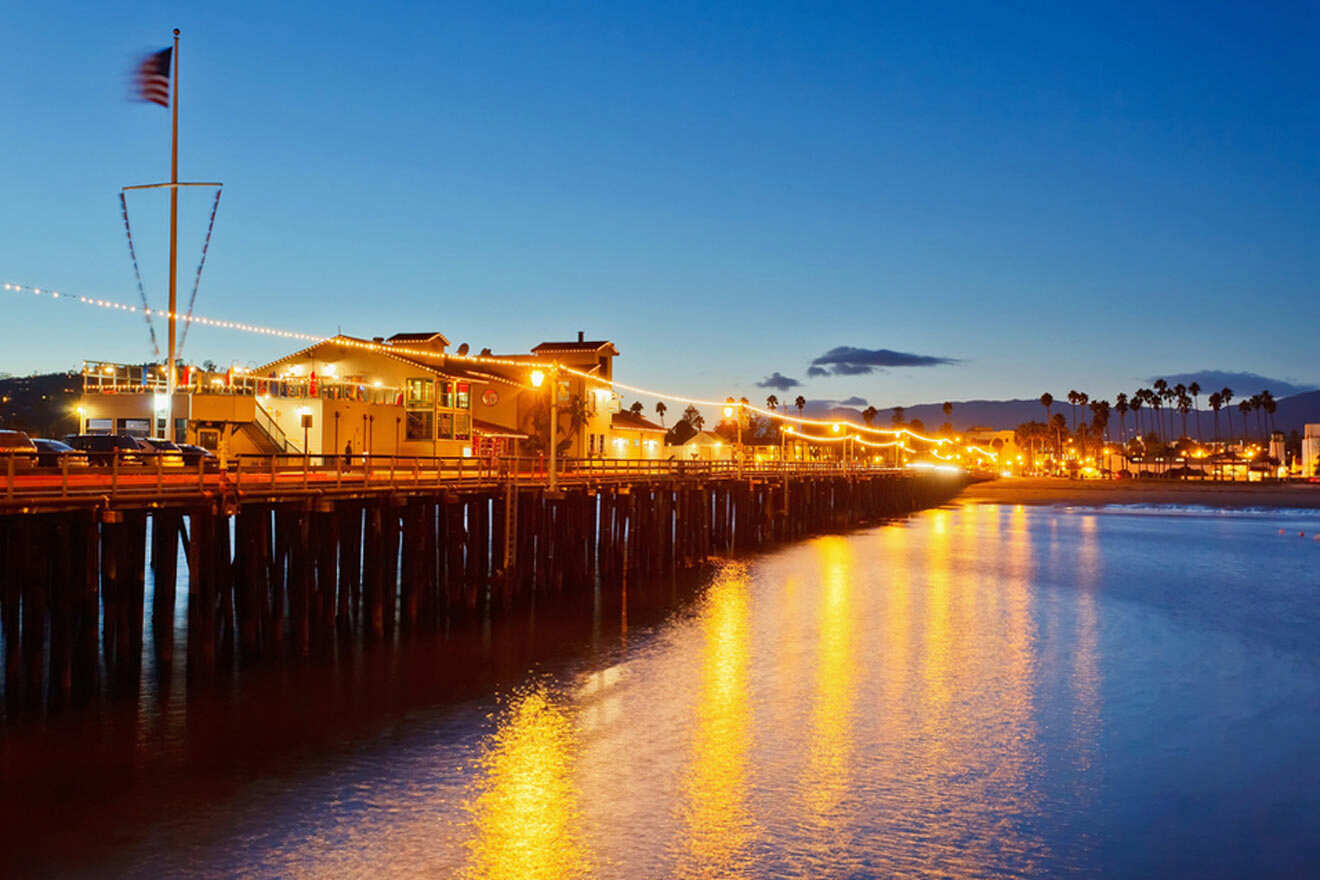 a pier at night with lights reflecting off the water