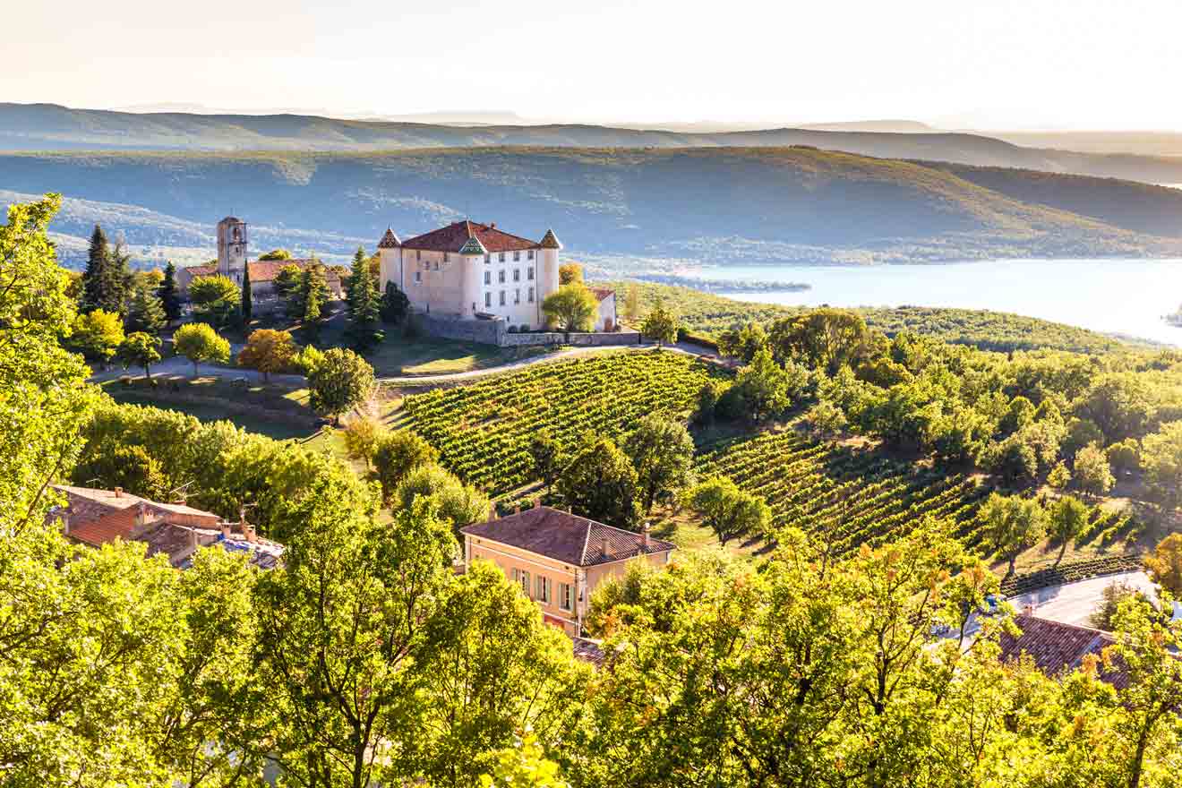 a large white building sitting on top of a lush green hillside and a vineyards
