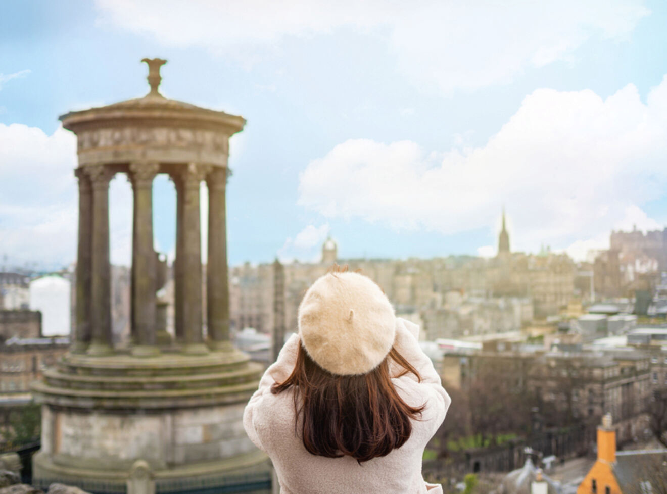 a woman standing on top of a hill looking at a city