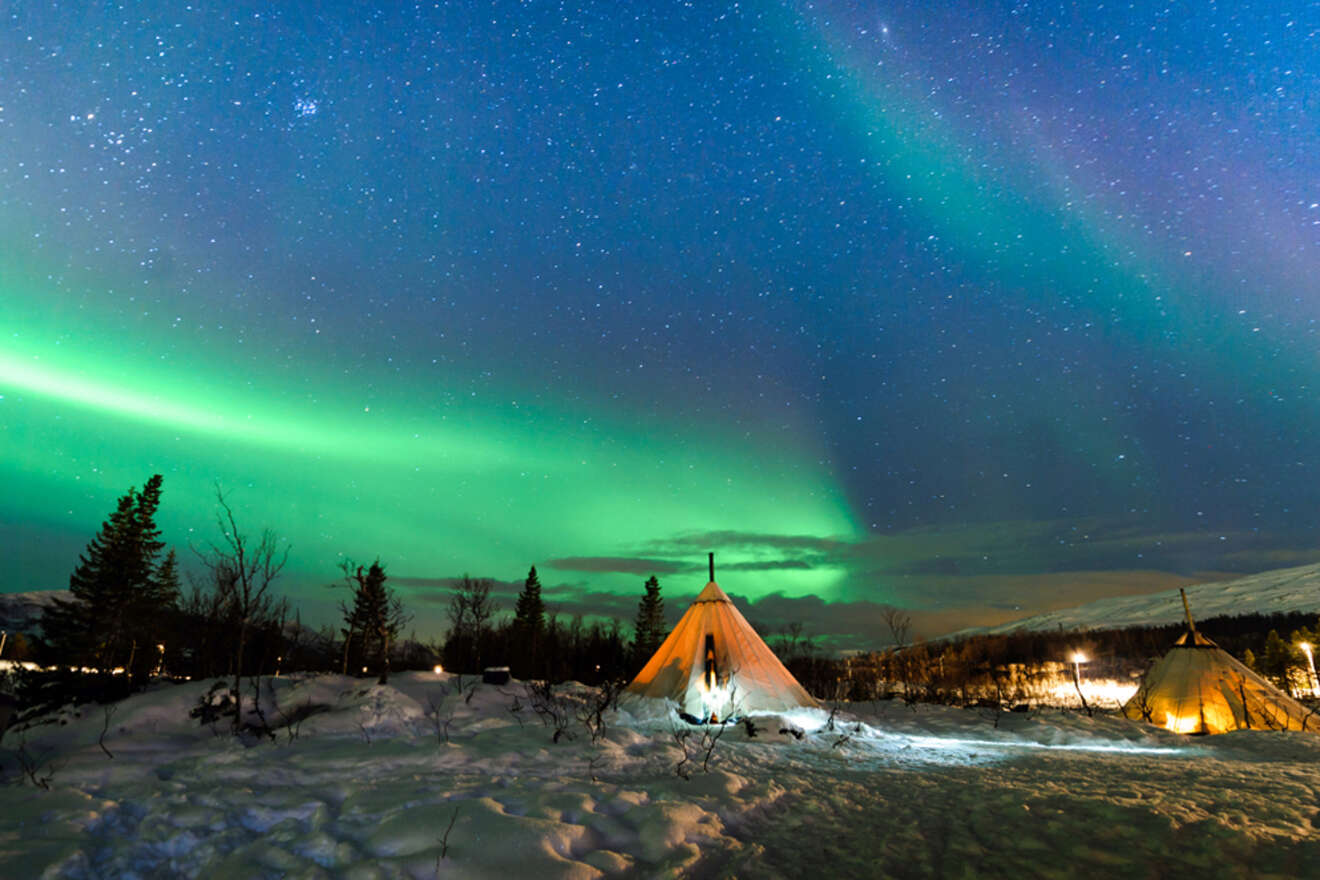 tents on a snowy field with the northern lights on the sky