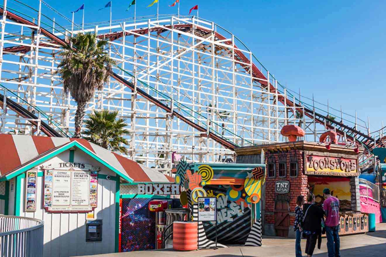 shops in a theme park with a rollercoaster in the background