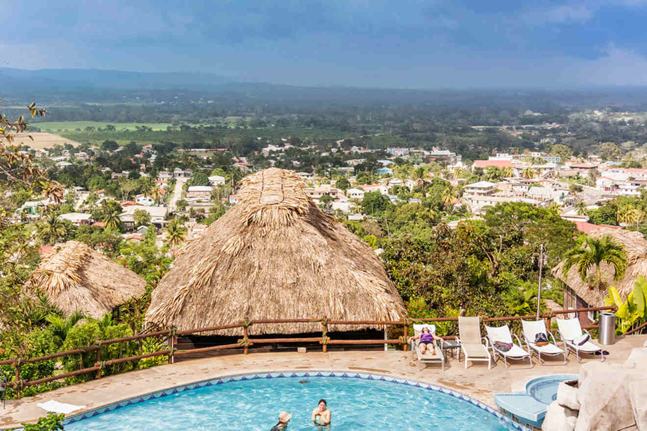 a pool with a thatched roof overlooking a city