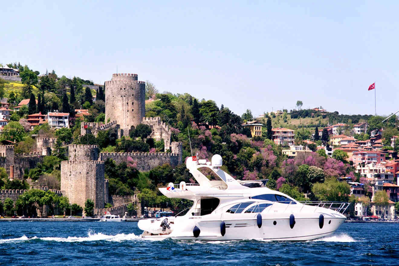a large white boat in a body of water with Rumeli Fortress in the background