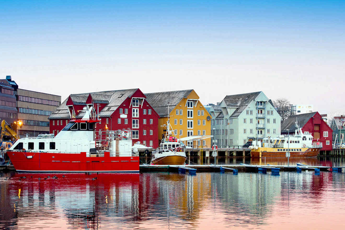 a red and white boat docked in a harbor and colorful houses in the background