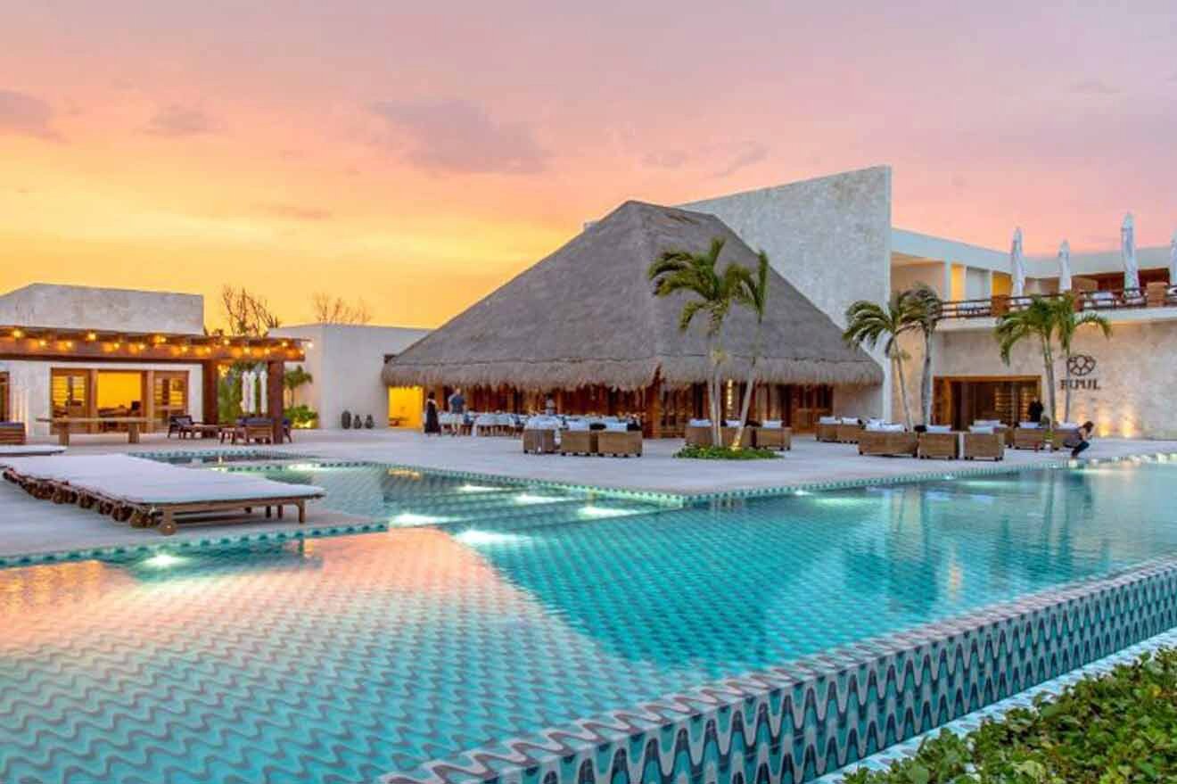 a resort with a swimming pool surrounded by palm trees at sunset