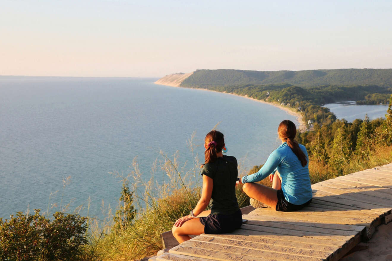 a couple of women sitting on top of a wooden platform looking at the water