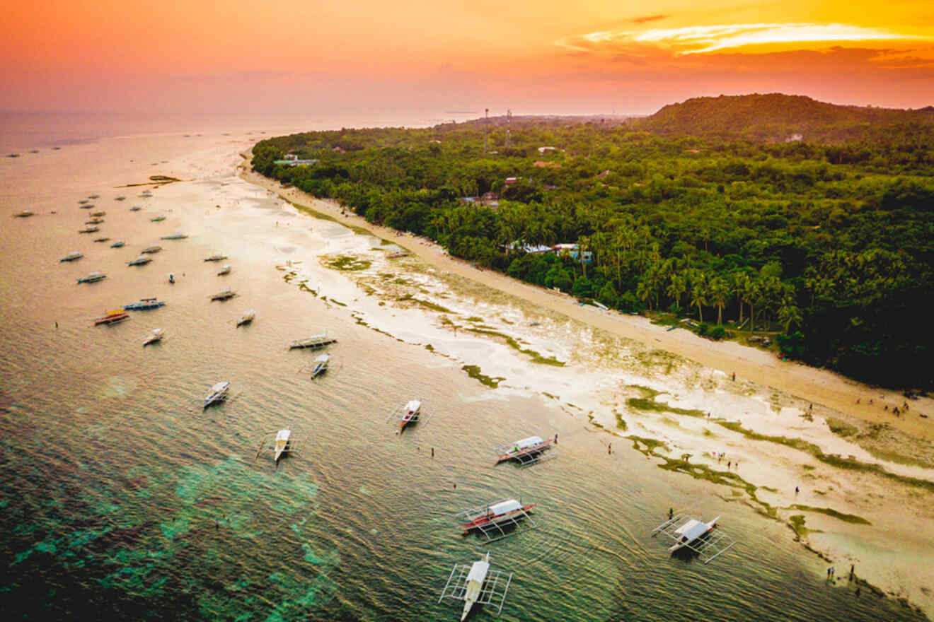 boats floating in the ocean near the coast on a sunset