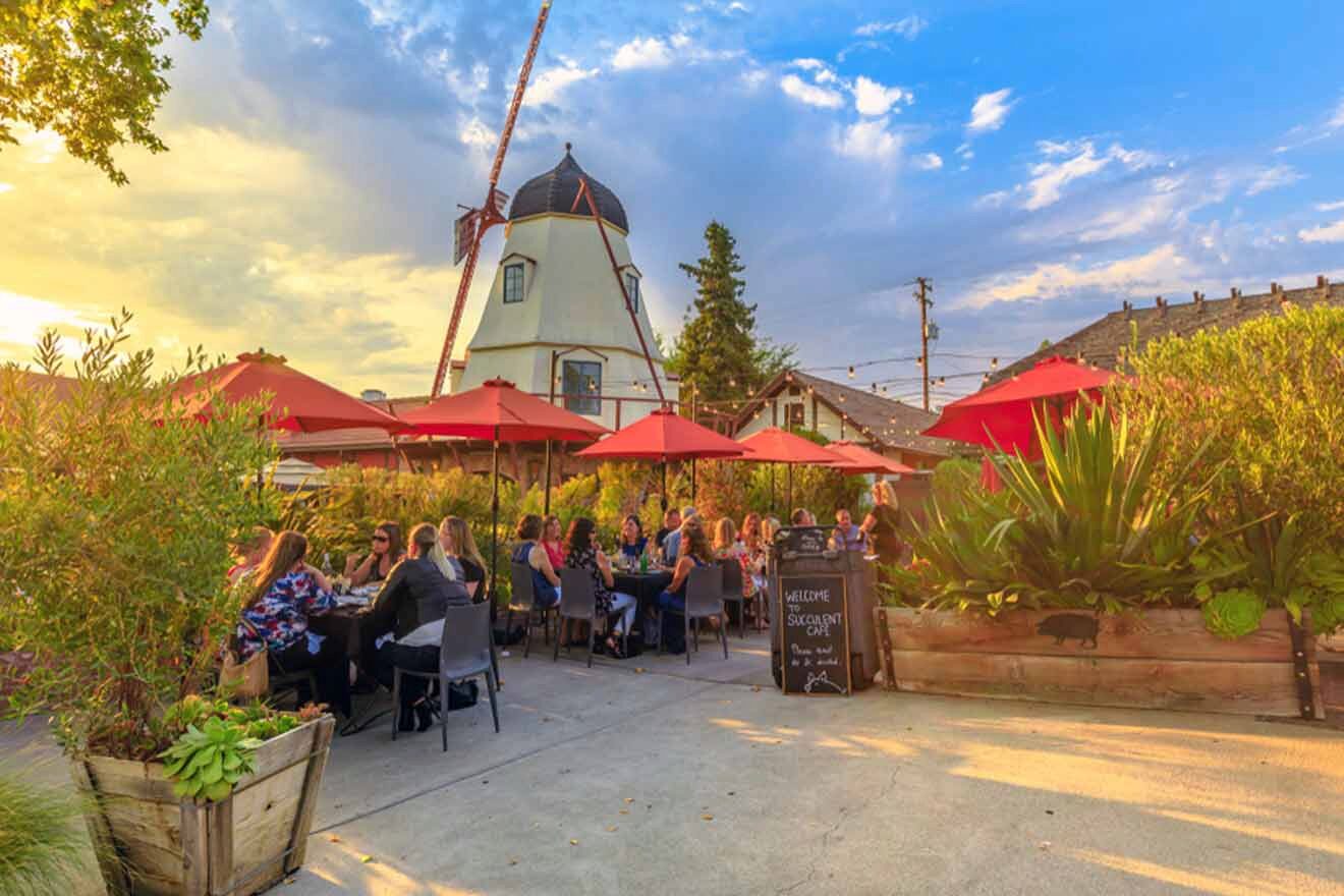 a group of people sitting around a table with red umbrellas