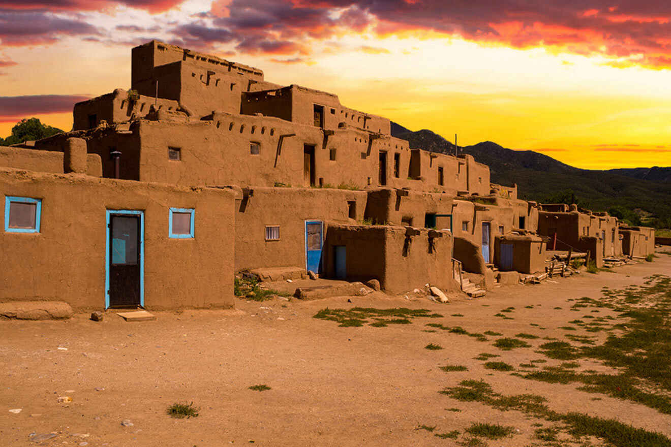 a group of adobe buildings sitting on top of a dirt field