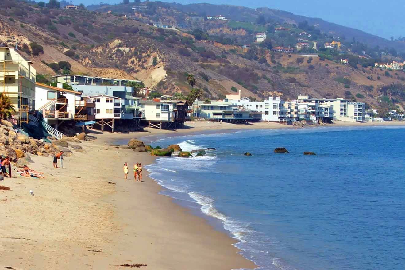 a picture of a beach with people walking on it and buildings in the background