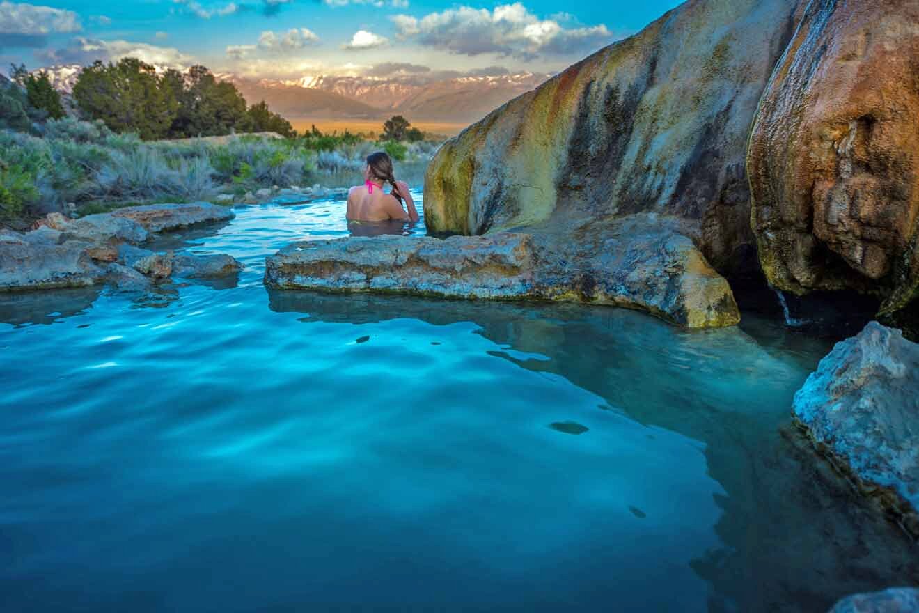 a woman sitting on a rock in a hot spring