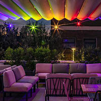 An outdoor patio with colorful lights and furniture.