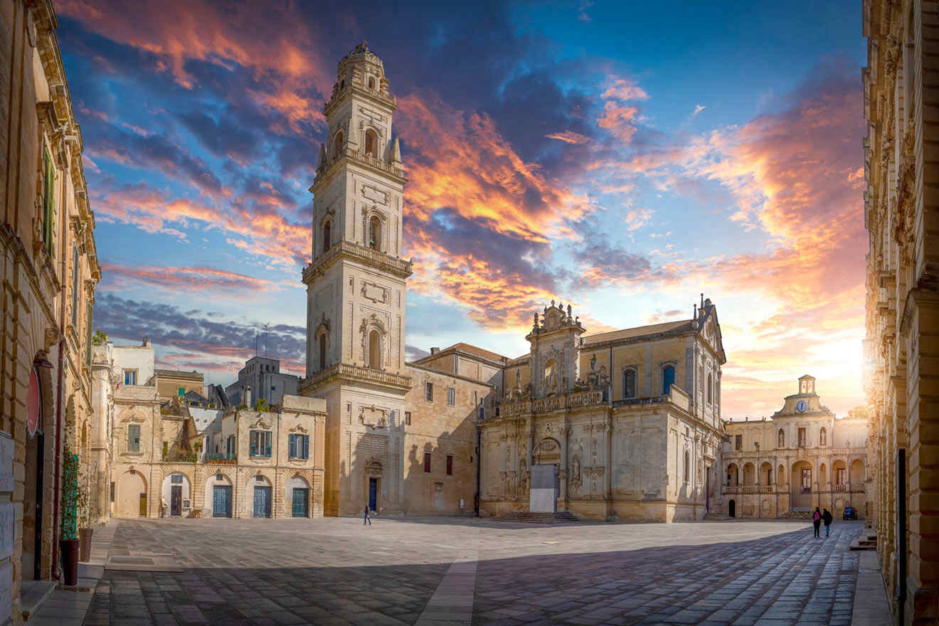 Historic square at sunset featuring a tall bell tower and ornate buildings with a dramatic sky.