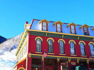 A red and yellow building in front of a snowy mountain.