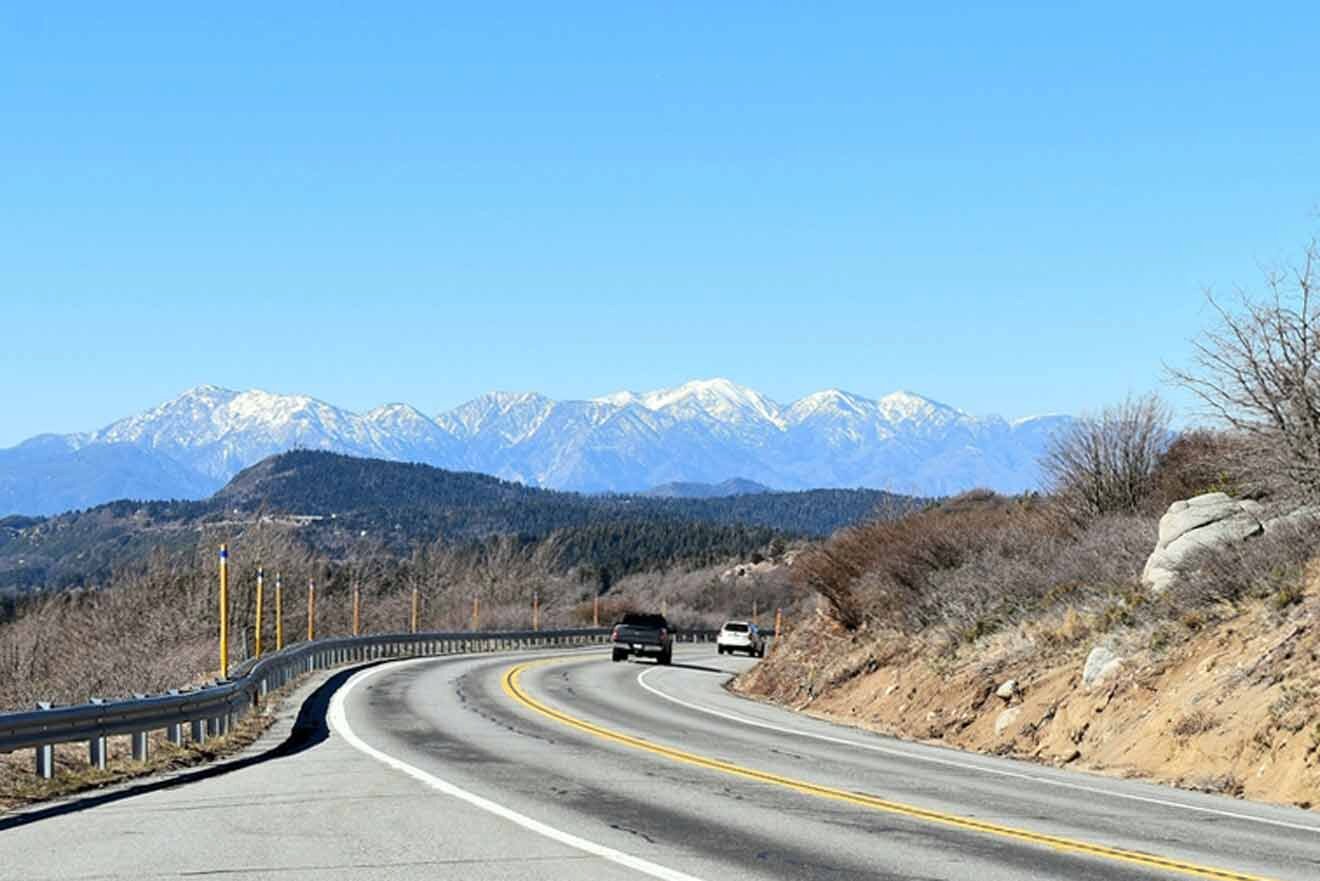 A truck driving down a road with mountains in the background.