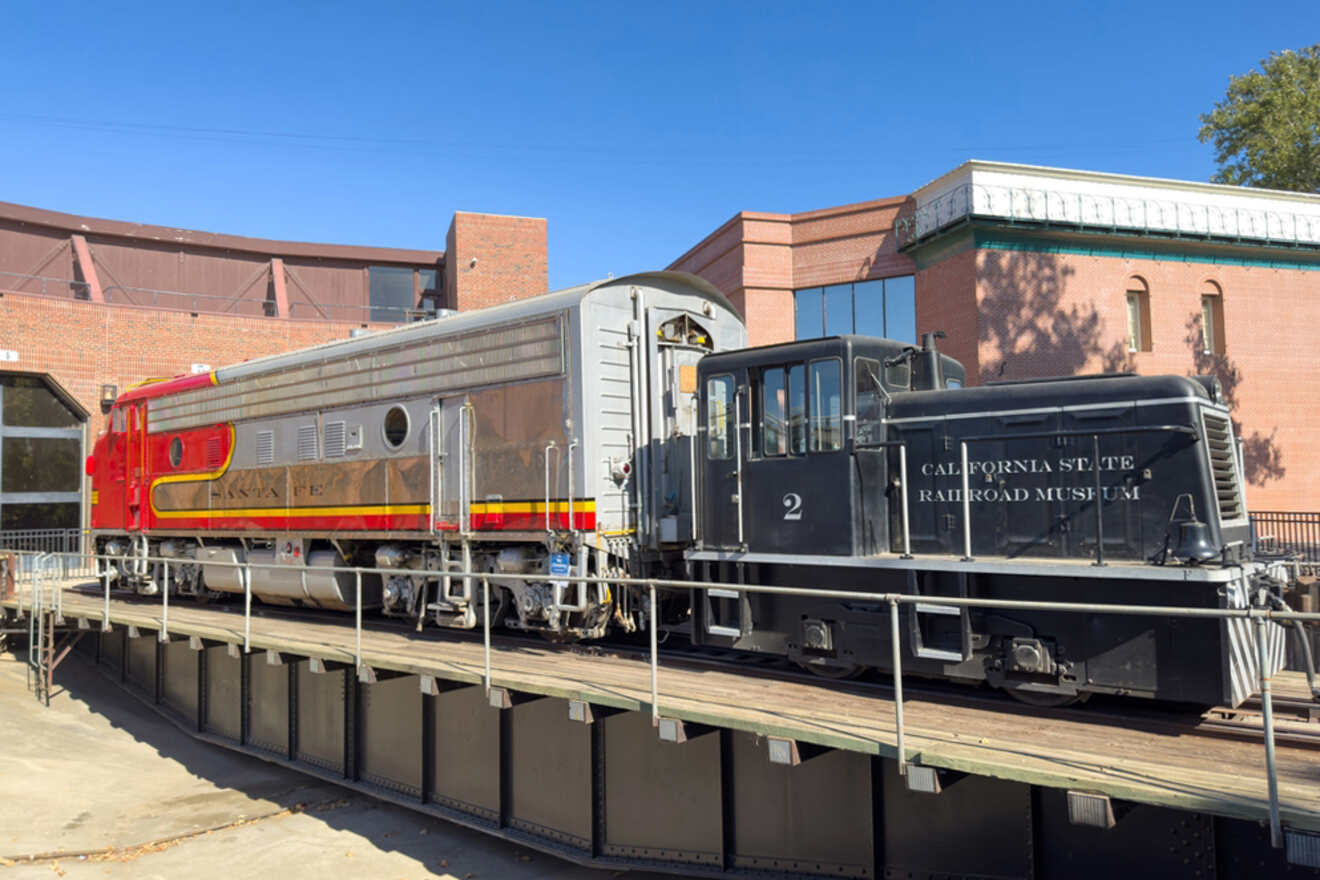 A red and black train on a track in front of a building.