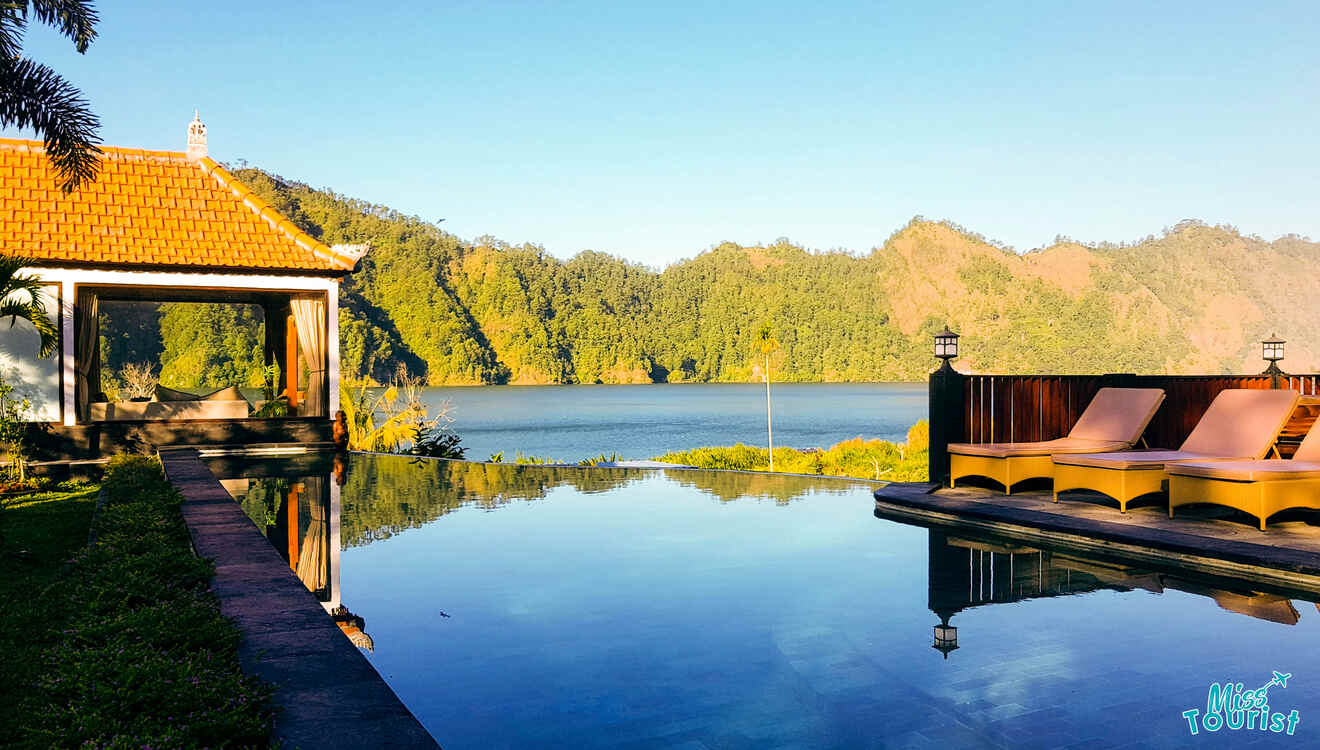 A pool with lounge chairs and a view of a lake.