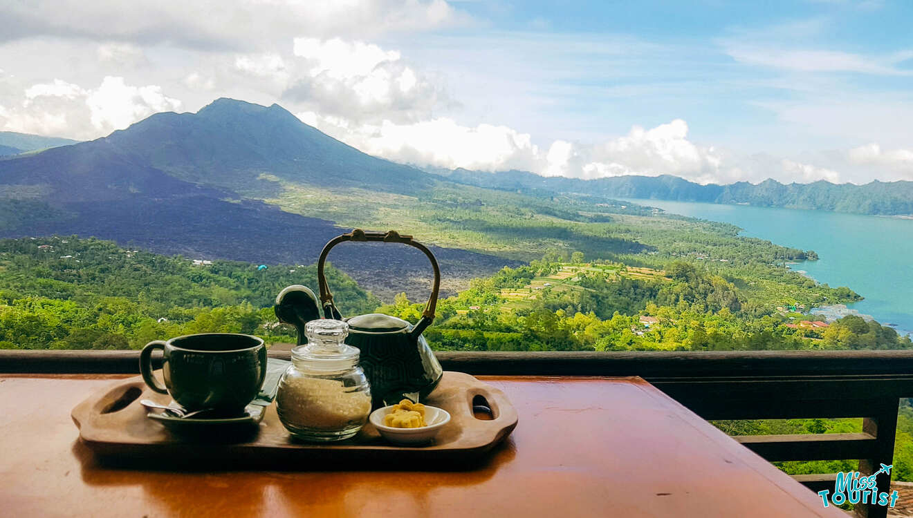 Tea and coffee on a table with a view of a lake.