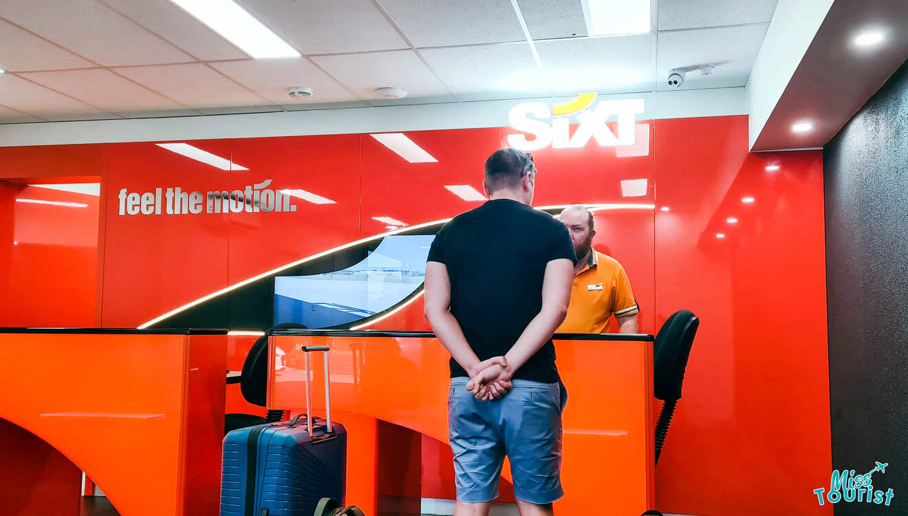 A man standing at the front desk of a SixT office.